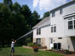 Zach of Complete Pressure Wash power washing a vinyl-sided house